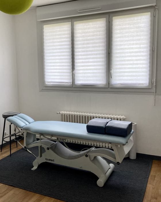 Salle de consultation du cabinet : table d'ostéopathie claire devant une grande fenêtre